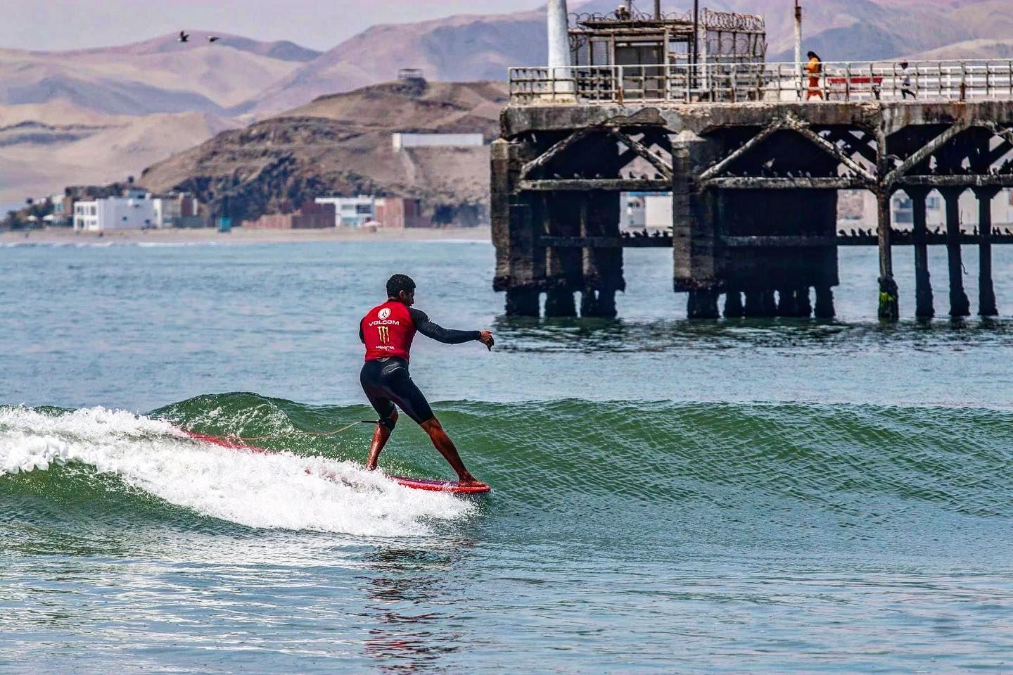 Surfista corriendo una ola frente al muelle de Cerro Azul