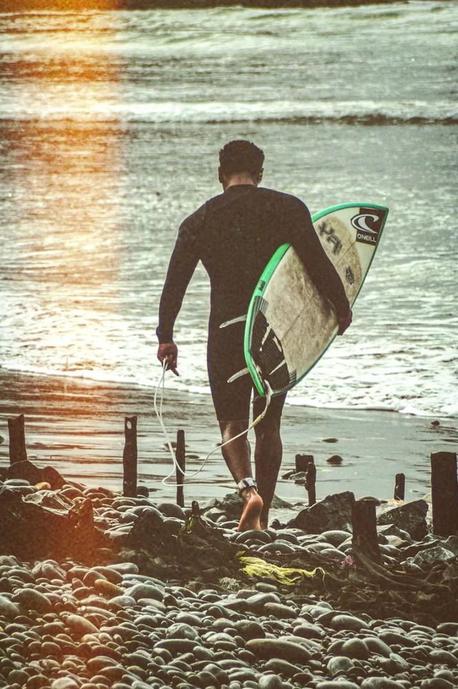 Surfista caminando hacia el mar con su tabla
