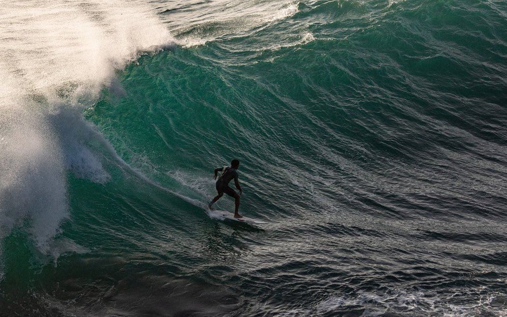 Surfista bajando una pared verde