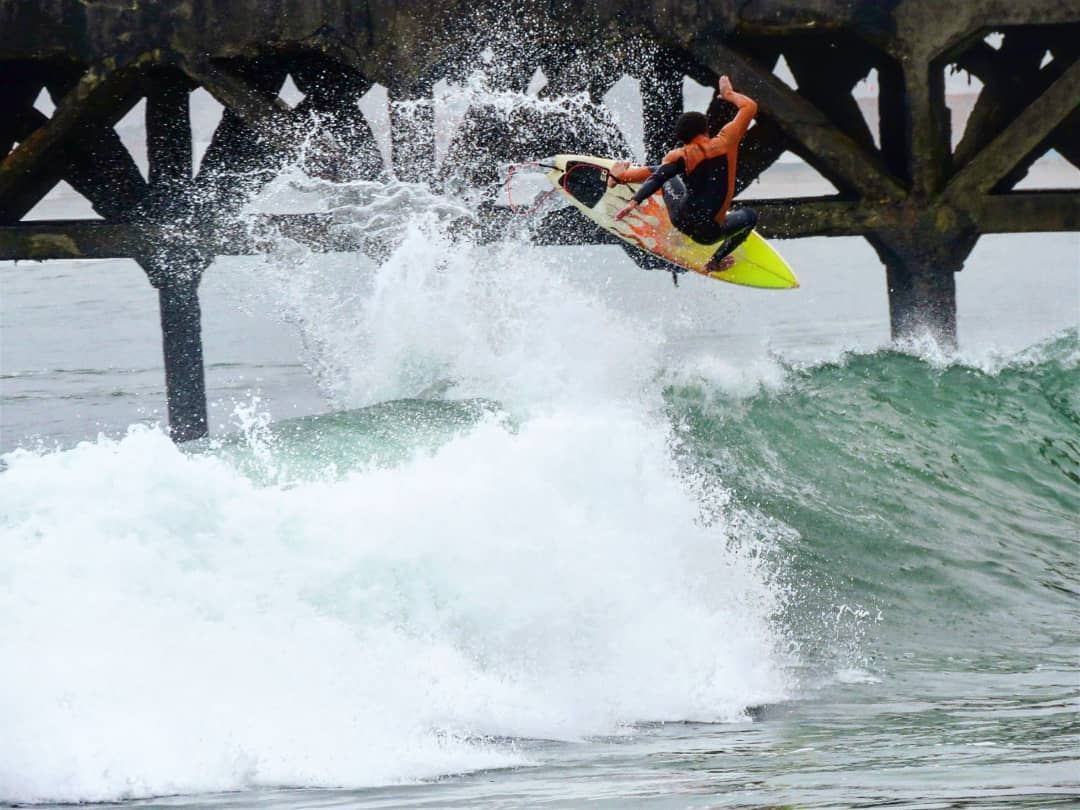 Surfista haciendo un aéreo junto al muelle, con marcas de análisis